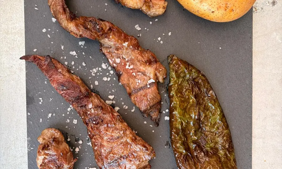 Secreto ibérico a la brasa con patata asada y pimientos en Mesón Los Monteros